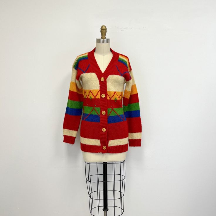 "Vintage 70s cardigan sweater featuring; a v neck long sleeves buttons down the front with wooden buttons with a longer cut in a horizontal stripe with a zig zag pattern stitched on the front ribbed at the neckline, cuffs, and hem of a mid weight, acrylic knit in primary colors of red, yellow, green, royal blue and off white labeled \"Knitmakers\" and tagged a size small, measurements when laid out flat are; 16 1/2 inches from pit to pit 19 3/4 inches sleeves 16 inches at the waist 13 1/2 inches Striped Long Sleeve Cardigan With Buttons, Retro Multicolor V-neck Sweater, Multicolor Retro V-neck Sweater, Retro Winter Cardigan With Buttons, Retro Winter Cardigan With Button Closure, Vintage V-neck Cardigan With Button Closure, Vintage V-neck Cardigan With Buttons, Retro V-neck Cardigan For Fall, Retro V-neck Winter Outerwear