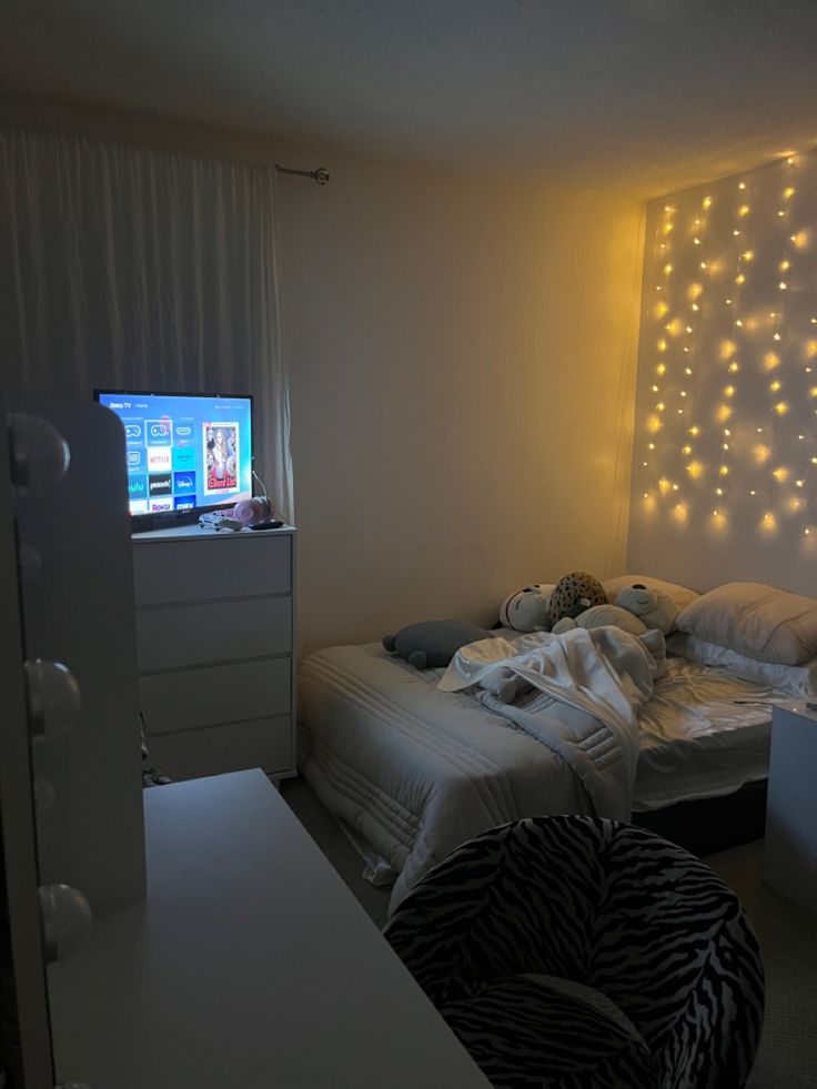 a bed room with a neatly made bed and a flat screen tv on the wall