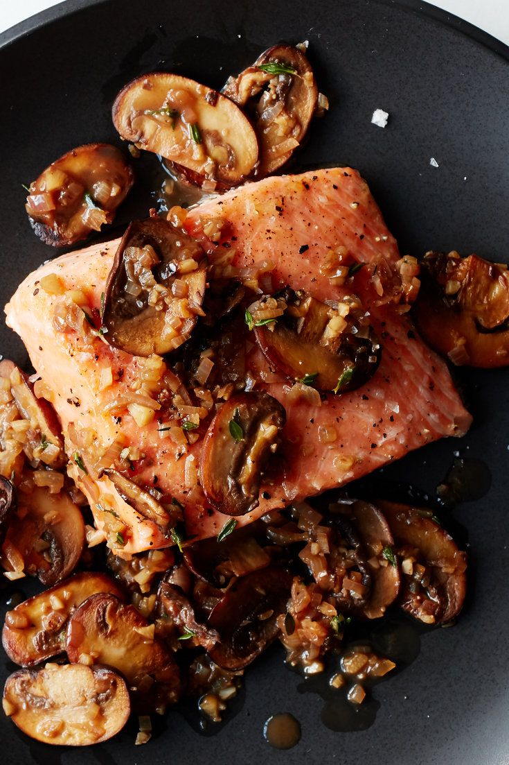 a black plate topped with meat and mushrooms