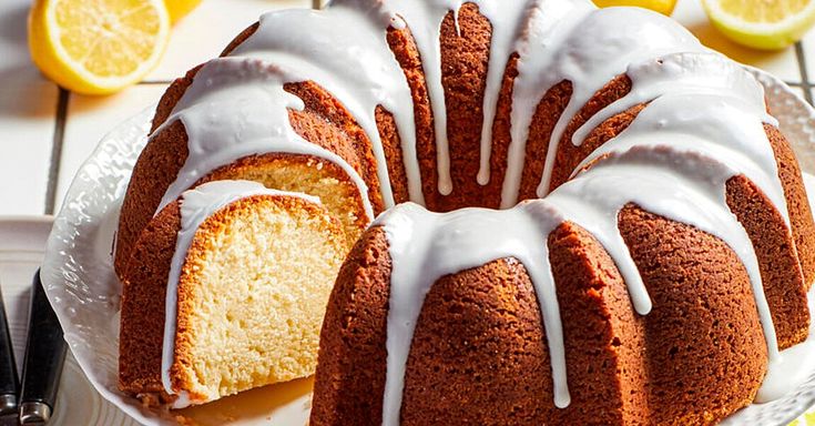 a bundt cake with white icing on a plate next to sliced lemons