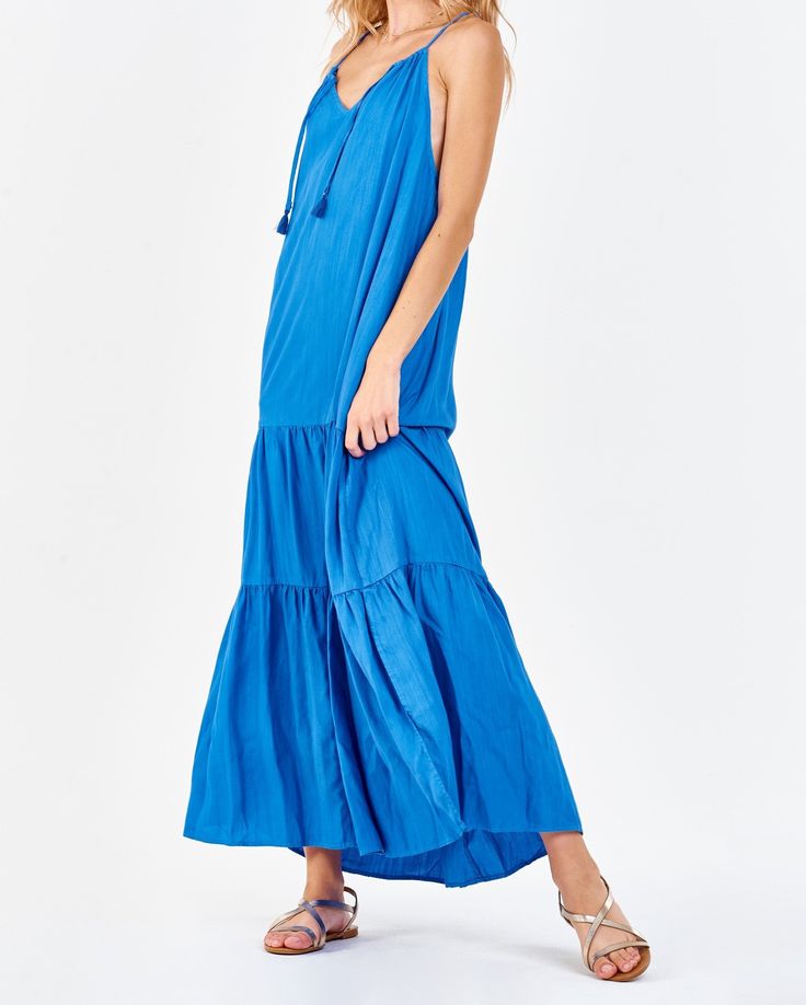 Strap halter maxi dress with side vents, cinching neck ties, deep back keyhole & armhole opening, tiered skirt. Simplicity in finest! Timeless exhibition of grace & serenity! Solid color woven on relaxed fit.Body length from HPS: 51", Sleeve length: N/A, Bust: 43" (Size Small) 100% TENCEL Machine wash cold, Line dry Imported Bohemian Tiered Maxi Dress With Tie Straps, Bohemian Tiered Maxi Dress With Tie Back, Blue Bohemian Maxi Dress With Tiered Skirt, Blue Tiered Maxi Dress For Vacation, Blue Maxi Dress With Tie Straps For Vacation, Sleeveless Tie Back Tiered Beach Dress, Flowy Tiered Maxi Dress With Tie Back, Tiered Skirt Maxi Dress With Tie Back, Sleeveless Tie Back Tiered Dress For Beach