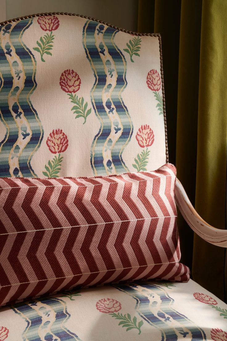 a close up of a chair with a pillow on it's back and a curtain in the background