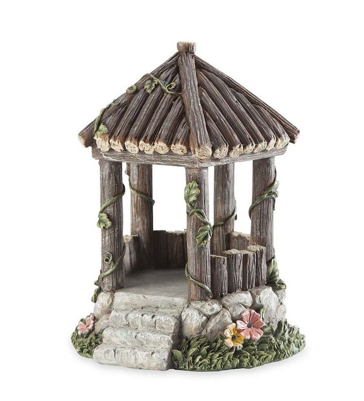 a small wooden gazebo sitting on top of a white ground next to rocks and flowers