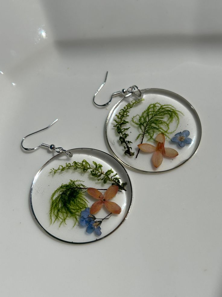 Gorgeous colorful wildflowers  with delicate ferns hand picked, pressed and dried for 2-3 days.   Once dried, I began the process of creating one of kind pieces which are preserved in a high quality non-toxic two part resin.  They are set in an open back hoop bezel, measuring 1-5/8 inch in diameter with silver earring wires. They are lightweight, beautiful and perfect for any occasion. ** Happy to answer any questions you may have, and invite you to share your thoughts on these special botanical earrings OR if you're interested in a custom or personalized version! Send me a message - I love connecting with customers! ** As in nature, there may be differences in shape, color or foraged elements.  Each item is unique therefore the piece you receive might not be exactly as shown in photos.  T Botanical Flower Earrings With Flower Charm, Botanical Flower Earrings With Birth Flower, Nature-inspired Dangle Flower Earrings, Nature-inspired Hypoallergenic Flower Dangle Earrings, Botanical Flower Drop Earrings, Bohemian Dangle Earrings With Pressed Flowers, Botanical Flower-shaped Hypoallergenic Earrings, Nature-inspired Flower Earrings, Botanical Style Flower Hypoallergenic Earrings