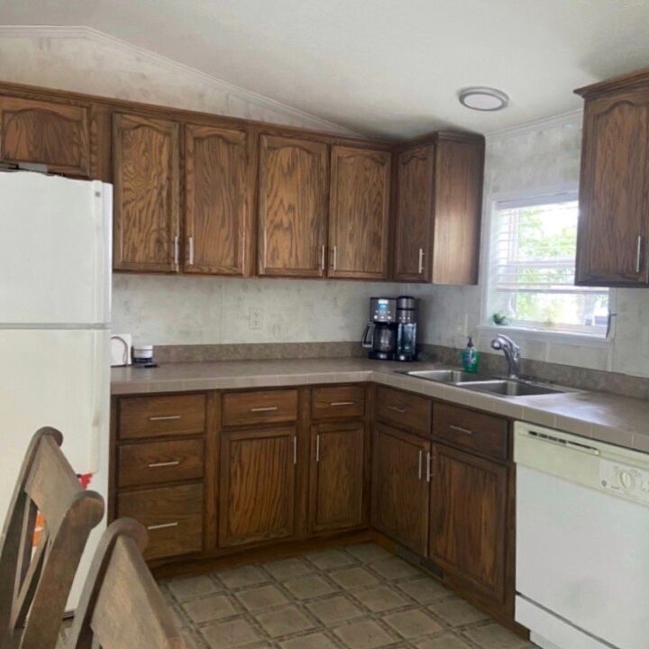 a kitchen with wooden cabinets and tile flooring, along with a white refrigerator freezer