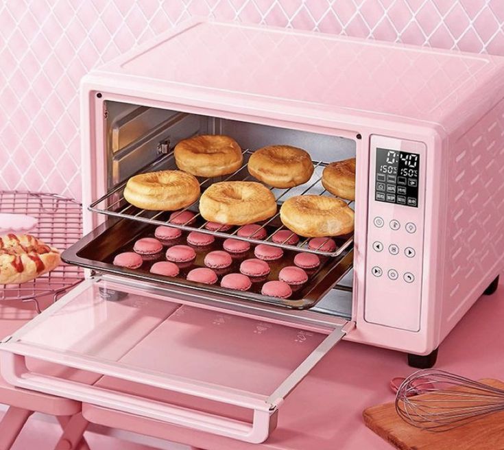 a pink toaster oven filled with lots of donuts