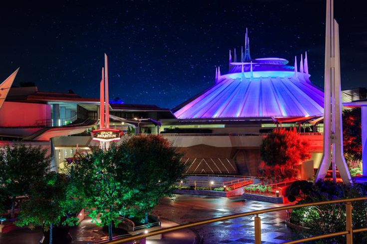 an amusement park at night with lights on and trees in the foreground as well