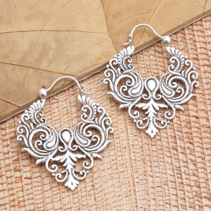 Inspired by the beauty of a well-tended garden Suar Dwipayana in Bali designs these exquisite hoop earrings. The artisan hand crafts the earrings from sterling silver in a combination finish fashioning tendrils of precious metal that curl into an elegant symmetrical design. Ornate Handmade Hoop Earrings, Handmade Ornate Hoop Earrings, Bohemian Sterling Silver Jewelry With Artistic Design, Metal Hoop Earrings With Intricate Dangle Design, Bohemian Silver Earrings With Artistic Design, Vintage Silver Hoop Earrings With Intricate Design, Elegant Oxidized Hoop Earrings For Festival, Silver Artisan Earrings With Artistic Design, Artisan Silver Dangle Hoop Earrings