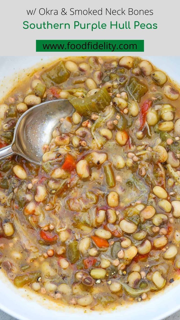 a white bowl filled with beans and other vegetables next to a spoon on top of a table