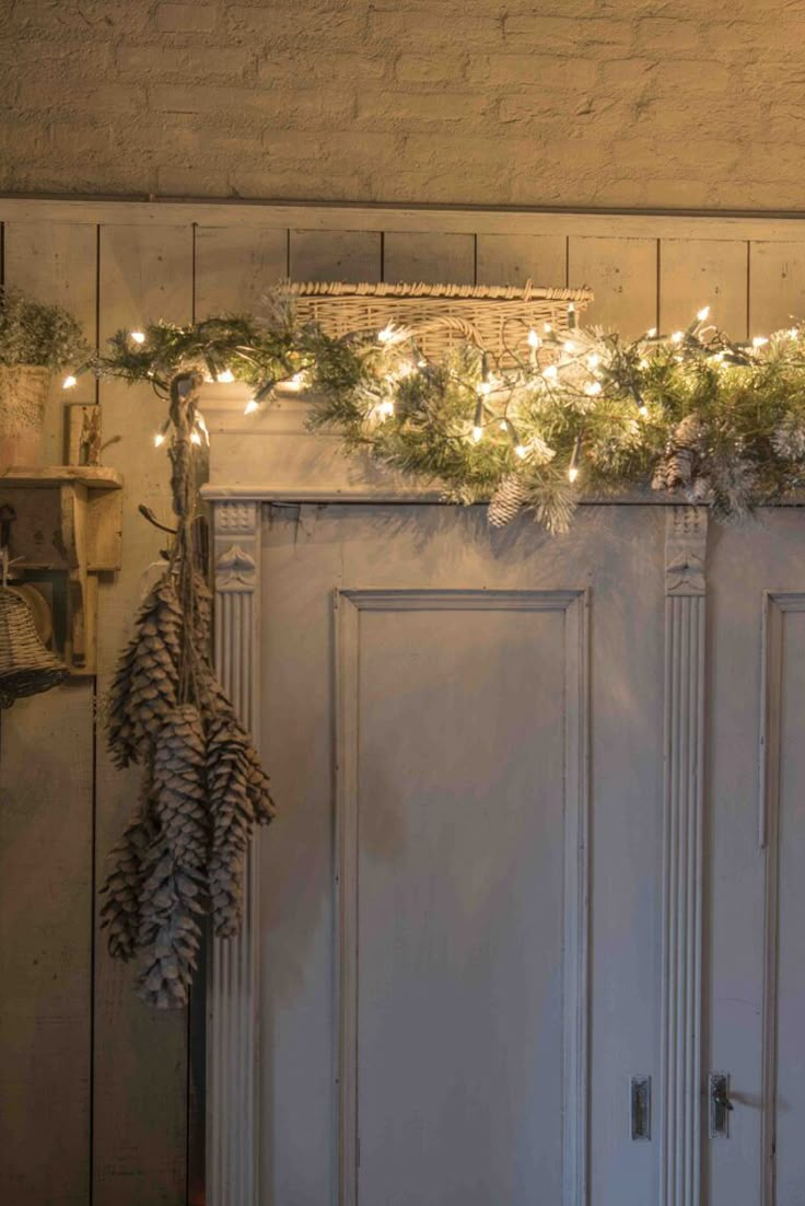 christmas lights are hanging from the top of an old white door with pine cones on it