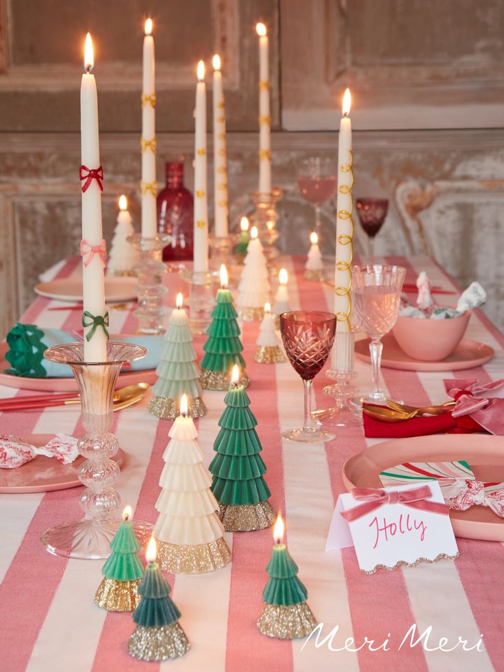 a table set for christmas dinner with candles and place cards on the plates, napkins and glasses