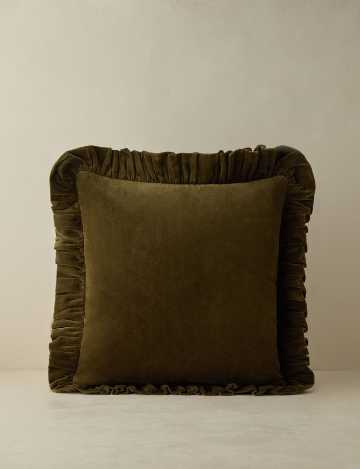 a brown pillow with ruffled edges on a white surface