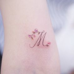 a small tattoo with the letter m on it