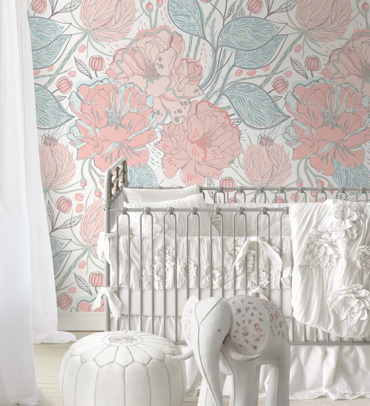 a white crib in front of a floral wallpaper with pink flowers on it