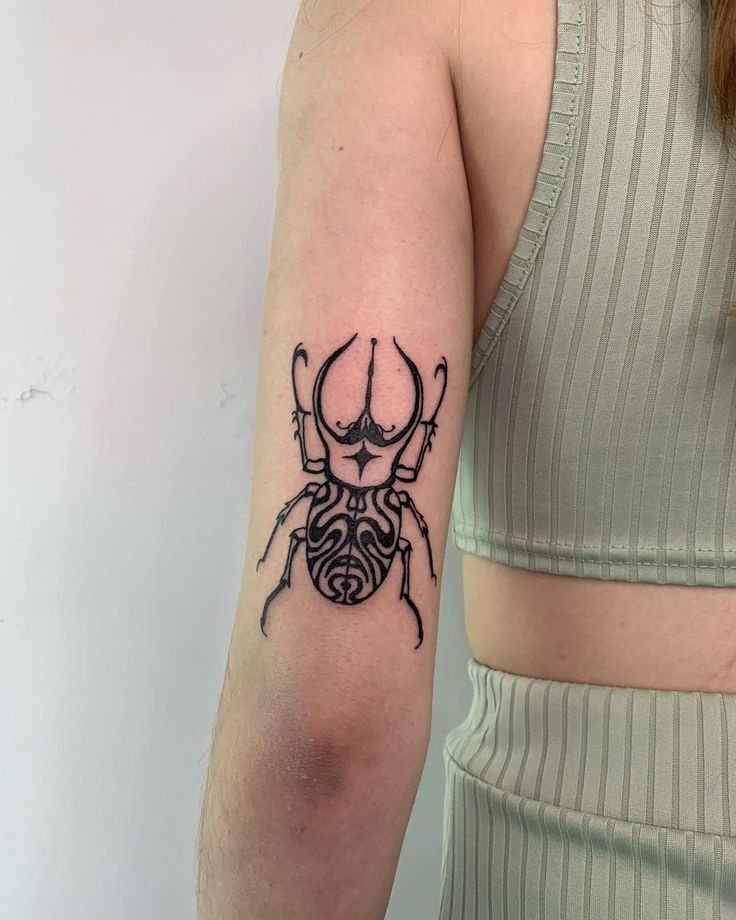 a woman's arm with a tattoo on it that looks like a bug or spider