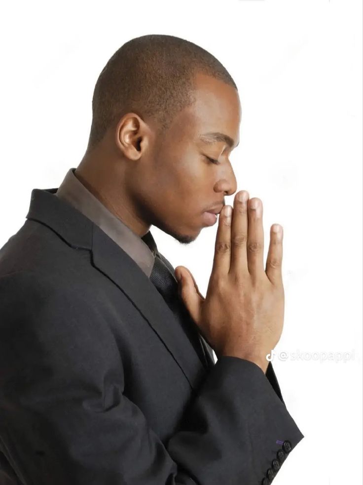 a man in a suit is praying with his hands together