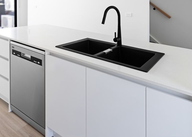 a kitchen with white cabinets and stainless steel sink, black faucet over the dishwasher