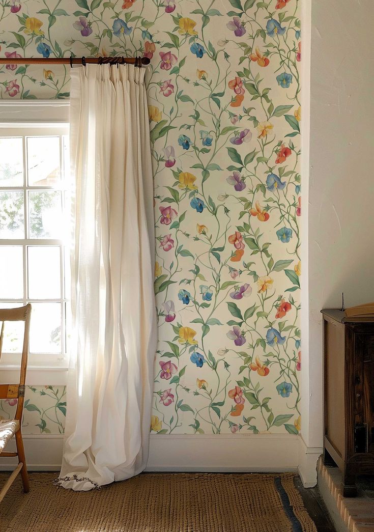 a room with floral wallpaper and white curtains