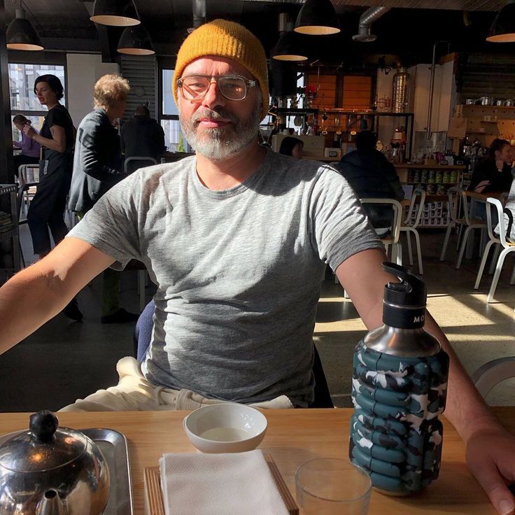 a man sitting at a table with a water bottle in front of him and a teapot