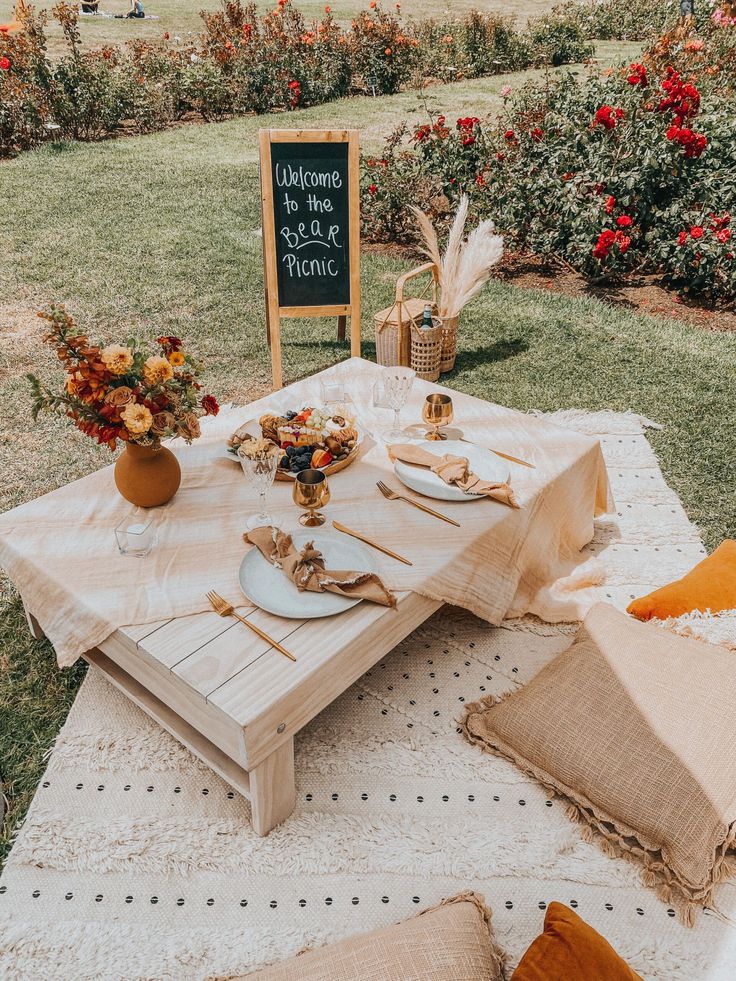 a table set up with plates and napkins on it in the middle of a field