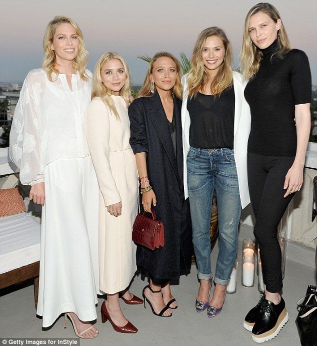 four women posing for the camera at an event in front of a cityscape