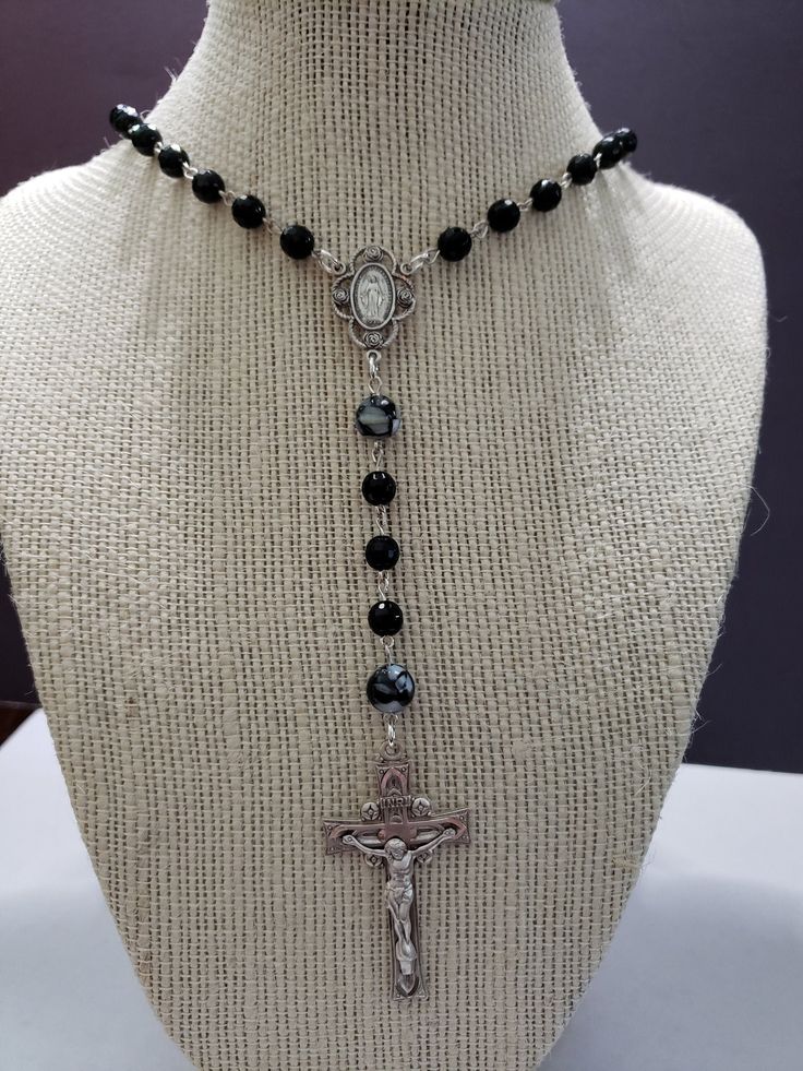 Each sterling silver link is hand turned. Faceted 6-mm black onyx beads are used for the Aves, and 8-mm black and white shell pearls are used for the Paters. Both the crucifix and the center are sterling silver. The crucifix measures 1 1/2". Necklace length is 28 3/4". Black Sterling Silver Jewelry With 8mm Beads, Silver Rosary With Black Beads And Crucifix, Black Beaded Crucifix Jewelry, Silver Cross Jewelry With Black Beads, Elegant Black Crucifix Jewelry, Silver Crucifix Jewelry With Black Beads, Black Sterling Silver Crucifix Jewelry, Onyx Bead, Black Onyx