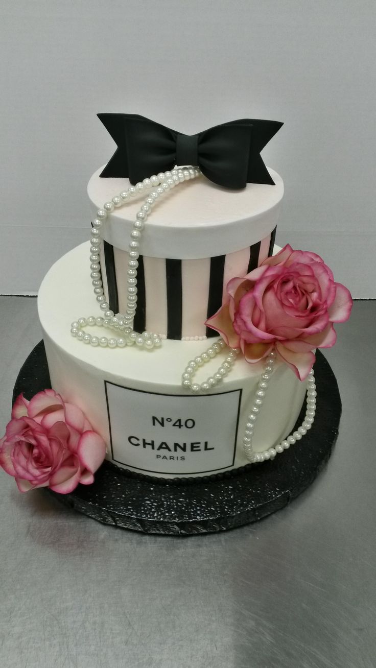 a chanel cake with pink roses and pearls on the top is decorated in black and white