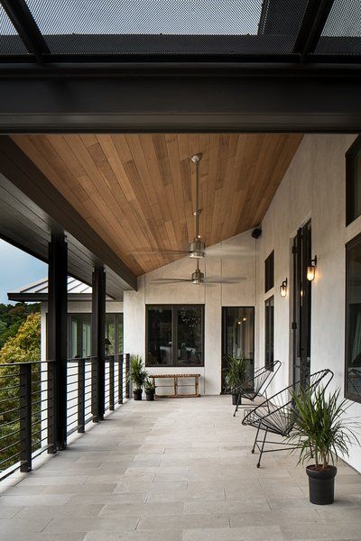 an outdoor covered porch with chairs and potted plants