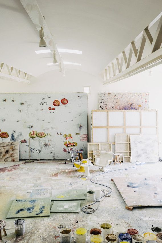 an artist's studio with paint, brushes and palettes on the floor in front of a white wall