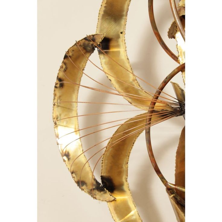 an artistic sculpture made out of metal and gold leaf shapes, on a white background