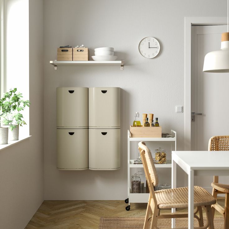 a kitchen with white walls and wooden flooring next to a dining room table filled with chairs