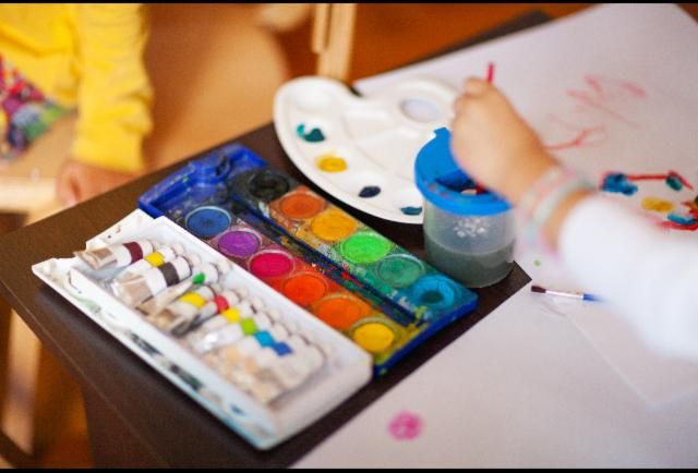 the child is painting on the table with watercolors