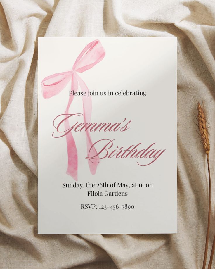 a birthday card with a pink bow on it sitting next to some brown grass and a white sheet