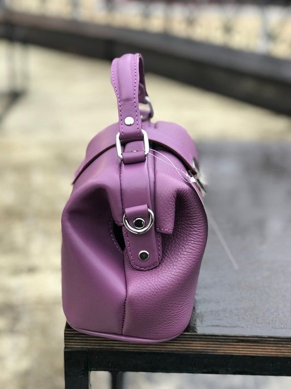 In the modern world, it is difficult to see a stylish lady without any accessory, where she could put everything necessary. For many years, bags made from natural materials have been very popular. This violet doctor style bag is created from genuine leather. Women's leather handbag always remains relevant, regardless of the style outfit or fashion trends. Such a satchel, shopper or tote bag has a zipper and very comfy as a crossbody shoulder accessory. This bright travel purse will be a great gi Modern Rectangular Purple Satchel, Modern Purple Rectangular Satchel, Purple Top Handle Box Bag For Travel, Purple Leather Shoulder Bag With Detachable Handle, Purple Leather Satchel, Purple Satchel Shoulder Bag For Office, Purple Leather Satchel With Detachable Strap, Purple Leather Satchel Bags, Purple Leather Rectangular Bag