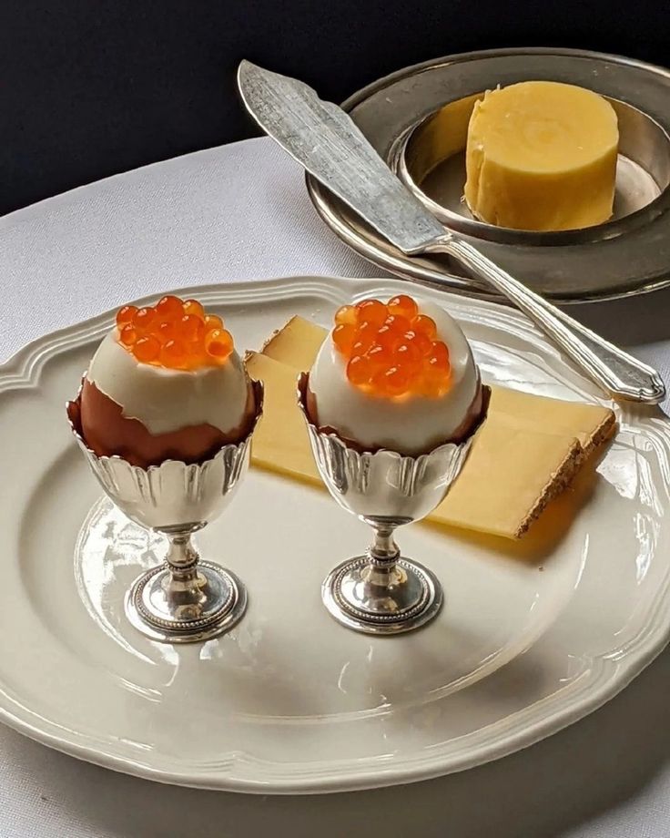 two desserts on a white plate with silver serving utensils