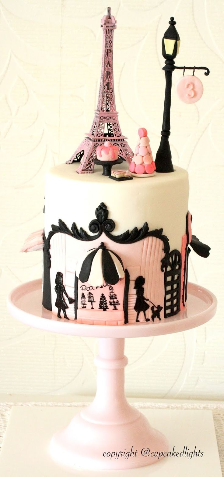 the cake is decorated with pink and black designs, including the eiffel tower