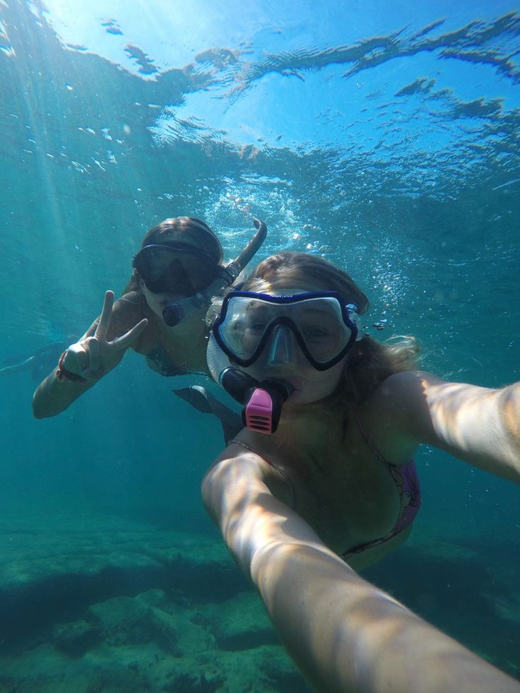 two people swimming in the water with snorkels on their heads and goggles on