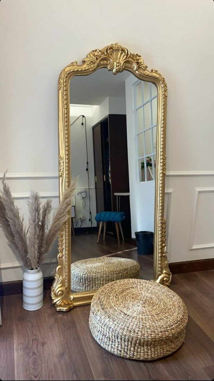 a large mirror sitting on top of a wooden floor next to a stool and vase