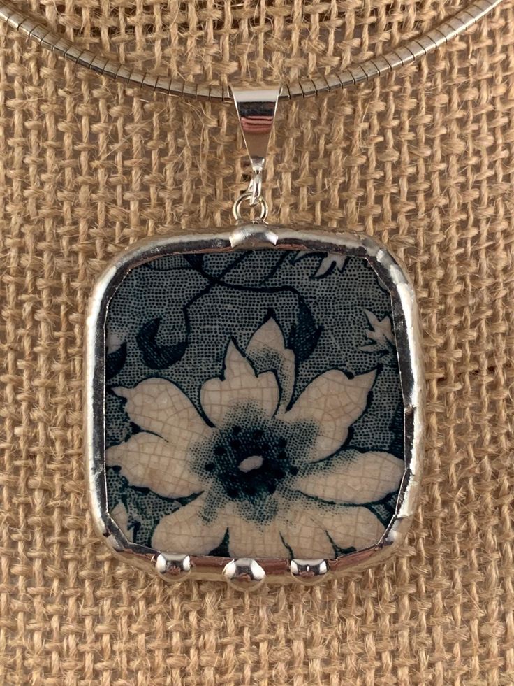 a square pendant with a flower on it