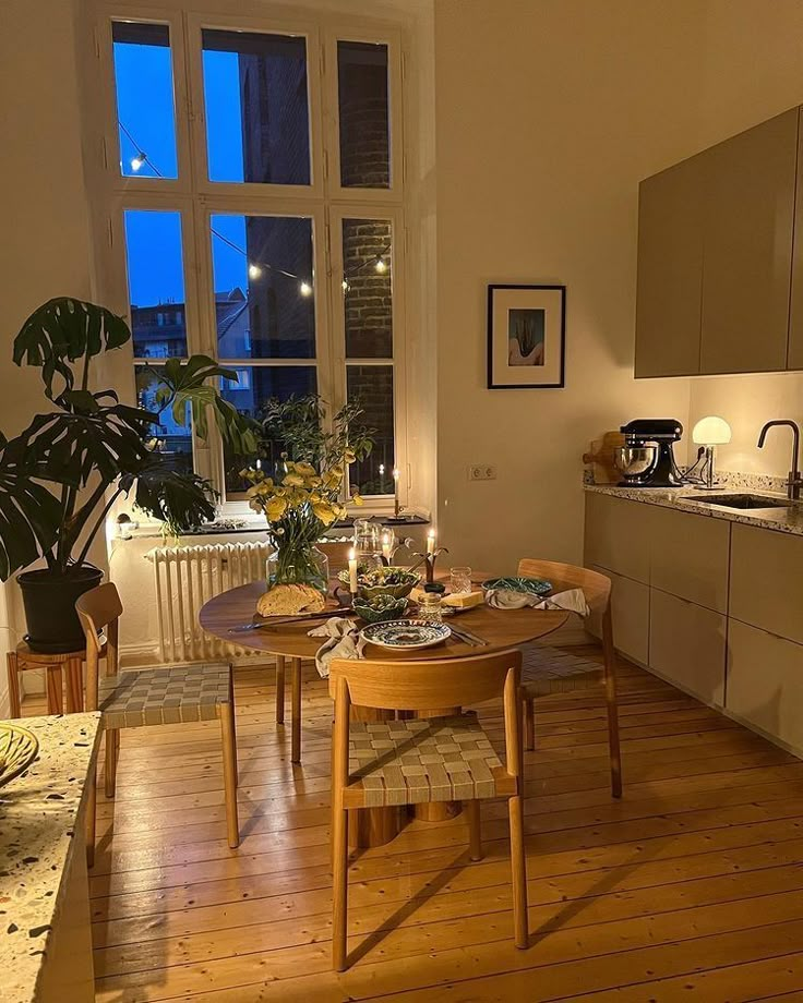 a table and chairs in a room with wood flooring next to a large window