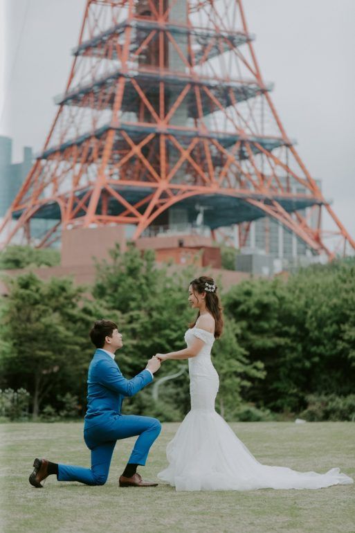 a bride and groom kneeling down to each other in front of the eiffel tower