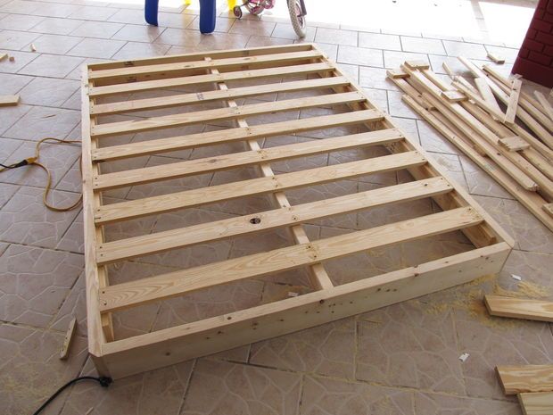 a wooden bed frame sitting on top of a floor next to other pieces of wood