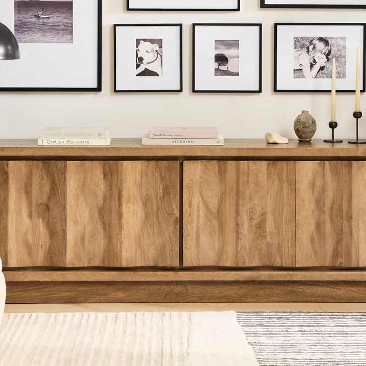 a living room with pictures on the wall and a sideboard in front of it