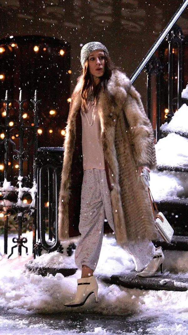 a woman is standing outside in the snow wearing a fur coat and slip - ons