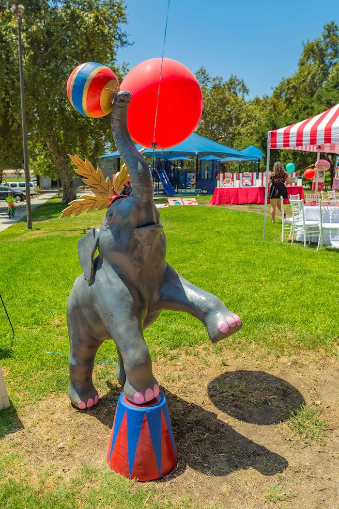 an elephant balancing on top of a red and blue ball with its trunk in the air