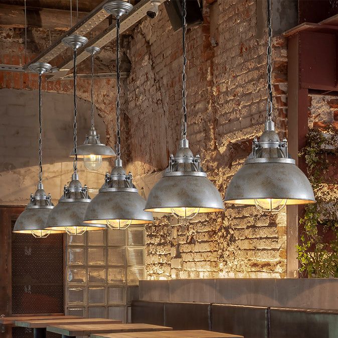 several lights hanging from the ceiling in an industrial style restaurant with brick walls and wooden tables