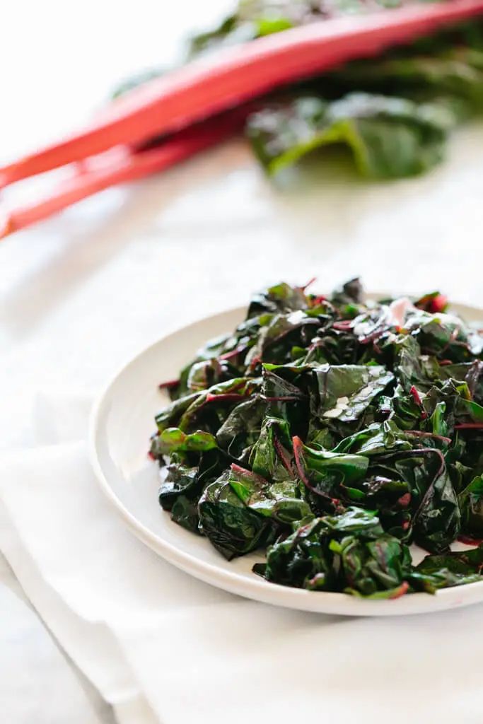 a white plate topped with greens on top of a table