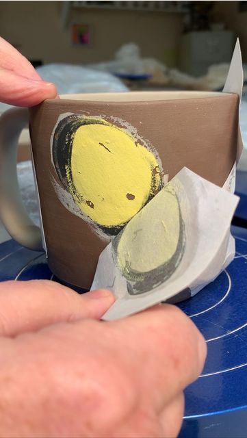 a person is holding a coffee mug with an image of a yellow bird on it