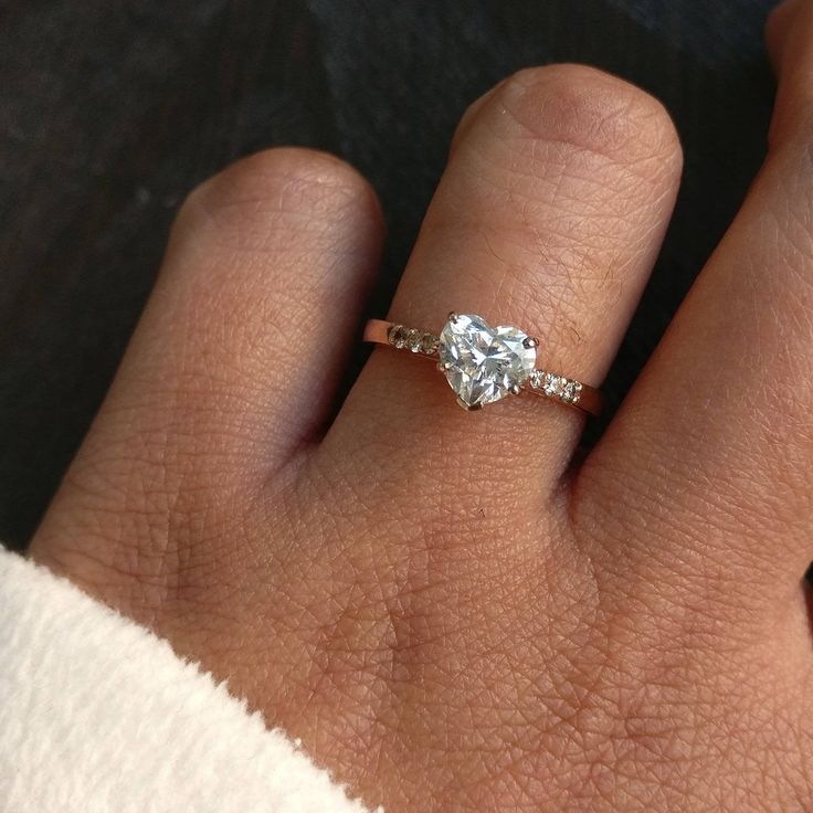 a woman's hand with a diamond ring on top of her left hand,