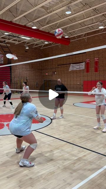 a group of people standing on top of a hard wood floor covered court playing volleyball